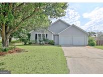 Charming gray home with a two-car garage, lush green lawn, and lovely landscaping at 10690 Tara Village Way, Joneboro, GA 30238