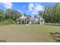 Charming white farmhouse-style home with a well-manicured lawn and inviting curb appeal surrounded by mature trees at 11807 Alcovy Rd, Covington, GA 30014