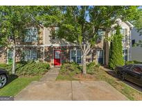 Charming townhome featuring stone accents, colorful door, mature trees and a convenient parking pad at 11439 South Grove Dr, Hampton, GA 30228