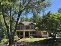 Charming brick two-story home with a welcoming front porch and beautifully landscaped front yard at 245 River Laurel Way, Woodstock, GA 30188