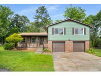 Split level house with a brick facade, two car garage, and landscaped front yard at 7455 Dover Ct, Riverdale, GA 30274
