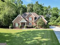 Charming brick home with a lush green lawn and mature trees, offering a serene and inviting curb appeal at 1315 Crane Ct, Mcdonough, GA 30252