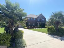 Elegant brick home featuring a long driveway and well-manicured front yard with mature palm trees at 1869 Schofield Dr, Hampton, GA 30228