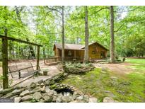 Beautifully landscaped log cabin with a charming front porch and mature trees at 349 Campground Rd, Mcdonough, GA 30253