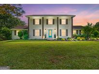 Traditional two-story white home with brown shutters, lush landscaping, and a vibrant blue front door at 75 Auburn Rd, Auburn, GA 30011