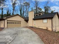 Charming single-story home features attached garage and neutral-toned siding, set in a wooded landscape at 1725 Sara Se Ct, Conyers, GA 30013