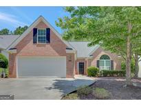 Charming brick home featuring an attached two-car garage and a well-manicured lawn with mature trees at 85 Parks Pl, Sharpsburg, GA 30277