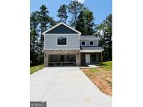 Two story home showing gray siding, brick foundation and large driveway surrounded by mature trees at 8035 Buffet, Riverdale, GA 30296