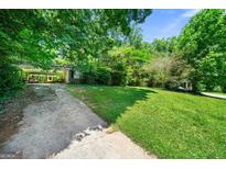 Exterior view of a home with a covered driveway and spacious front yard, offering lots of green space at 2257 Chestnut Log Loop, Lithia Springs, GA 30122