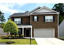 Two-story brick home featuring a gray garage door, black shutters, and a well-maintained lawn at 3993 Makeover Ct, South Fulton, GA 30349