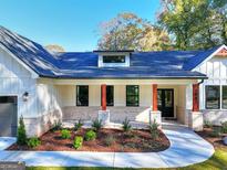 Beautiful front exterior with a walkway, manicured landscaping, and a covered porch with red accents and neutral brickwork at 1947 Clark Dr, Tucker, GA 30084