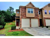 Charming townhome with a two-car garage, brick accents, and well-maintained landscaping in a residential neighborhood at 180 Oakland Hills Way, Lawrenceville, GA 30044
