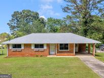 Charming single-story brick home with a well-manicured lawn and a convenient covered carport at 3548 Meadowview Ct, Rex, GA 30273