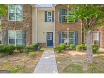 Charming townhome featuring stone and brick accents, a walkway, and lush landscaping at 1851 Grove Way, Hampton, GA 30228