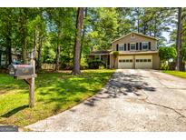 Charming two-story home with a two-car garage and long driveway, surrounded by lush greenery and mature trees at 6500 Wild Turkey Trl, Riverdale, GA 30296