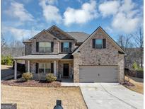 Charming brick home featuring a two-car garage, covered porch, and well-maintained landscaping at 10736 Southwood Dr, Hampton, GA 30228