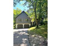 Charming two-story home with a two-car garage, gray siding, stone accents and mature trees at 143 Frances Dr, Dallas, GA 30157
