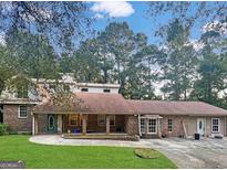 Charming brick home featuring a sprawling front yard with mature trees and covered porch perfect for relaxing at 258 Big Oak Rd, Whitesburg, GA 30185