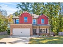 Inviting two-story home featuring a brick and red-sided facade, an attached two-car garage, and a well-manicured lawn at 475 Louise Way, Locust Grove, GA 30248