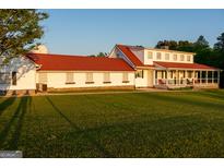 Expansive country home boasts a red roof, lush lawn, and charming front porch with ample seating at 4076 Airline Rd, Mcdonough, GA 30252