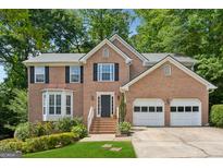 Charming brick home featuring a well-manicured lawn and an attached two-car garage at 1679 Summit Place Way, Loganville, GA 30052