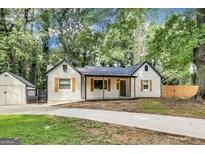 Charming home features a welcoming front porch, dark roof, detached garage, and spacious driveway at 500 Pomona Circle Sw, Atlanta, GA 30315