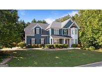 Charming two-story home with manicured lawn, stylish blue siding, and beautiful stone accents at 1210 Magnolia Park Cir, Cumming, GA 30040