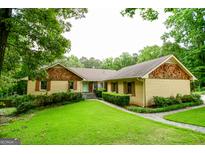 Charming brick home with cedar shake accents, shutters and a lush green lawn and stone walkway at 150 Sandy Ridge Trl, Fayetteville, GA 30214
