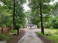 Quaint home featuring a charming white exterior, set back on wooded lot with a gated driveway at 6290 Cascade Palmetto Hwy, Fairburn, GA 30213