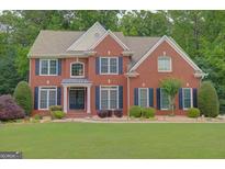 Charming two-story red brick home featuring dark shutters and a well-manicured front lawn at 165 Hidden Lake Dr, Fayetteville, GA 30215