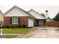 Charming brick home with well-maintained lawn, attached garage and black shutters at 165 Woodgate Cir, Fayetteville, GA 30214