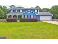Charming two-story blue home featuring a well-manicured lawn and a two-car garage at 108 Country Acres Ct, Mcdonough, GA 30253
