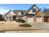 Charming home featuring a three-car garage, brick accents, manicured landscaping, and well-maintained lawn at 409 Brandy Ln, Mcdonough, GA 30253
