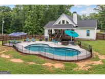 Backyard pool area with patio, lounge chairs, and a view of the home's deck and well-maintained lawn at 5745 Westwood Dr, Cumming, GA 30040