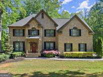 Charming two-story brick home with manicured lawn, inviting entrance, and professionally landscaped yard at 4680 Brighton Lake Dr, Cumming, GA 30040