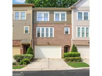 Charming townhome exterior featuring a brick facade, two-car garage, and manicured landscaping at 1300 Hopkins Dr, Decatur, GA 30033
