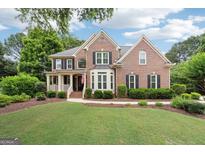 Charming brick home features a well-manicured lawn and inviting front porch at 151 Overhill Point, Alpharetta, GA 30005
