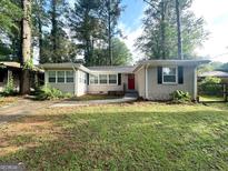 Charming single-story home with a neatly maintained lawn, a red front door, and lush surrounding trees at 3115 Pinehill Dr, Decatur, GA 30032