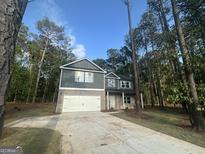 Two-story home featuring a gray facade, a brick-accented front, and an attached two-car garage with a long concrete driveway at 142 Tye St, Stockbridge, GA 30281