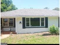 Charming single-story home featuring a gray roof and a freshly painted white brick exterior with black shutters and trim at 4814 Glenwood Rd, Decatur, GA 30035