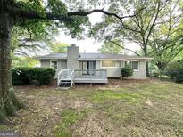 View of a ranch style home's backyard with a wooden deck and a partial brick chimney at 1918 Leigh Sw Dr, Conyers, GA 30094