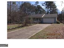 Charming single-story home featuring a long driveway and an attached garage, nestled amongst mature trees in a quiet neighborhood at 790 Mount Zion Nw Rd, Conyers, GA 30012