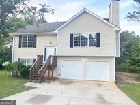 Charming two-story home with a two-car garage, wooden stairs, and vinyl siding at 4411 Ward Bluff Ct, Ellenwood, GA 30294
