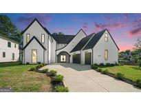 Stunning two-story home with a white brick exterior, black trim, driveway, and manicured landscaping at 115 Thome, Alpharetta, GA 30022