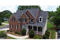 Charming two-story brick home featuring a welcoming front porch and professionally landscaped front yard with mature trees at 793 Fairington Pl, Lawrenceville, GA 30044