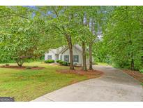 Charming home exterior featuring blue shutters, lush landscaping, and a long driveway, nestled among mature trees at 40 Wenham Ln, Sharpsburg, GA 30277