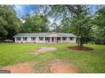 Charming single-story home with manicured lawn, bright red front door, and classic white columns at 3290 Ebenezer Se Rd, Conyers, GA 30094