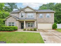 Charming two-story brick home featuring a well-maintained lawn and attached two-car garage at 12323 Styron Dr, Hampton, GA 30228
