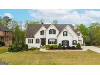 Elegant white home with dark shutters, surrounded by lush greenery and trees at 157 Waterlace Way, Fayetteville, GA 30215
