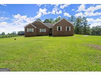 Charming brick home with lush green lawn, complemented by well-maintained landscaping and a serene countryside backdrop at 3950 Chattahoochee Rd, Cumming, GA 30041